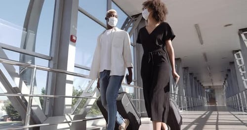 Travelers Walking Through Airport Terminal with Face Masks