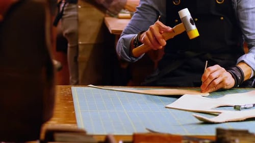 Mid section of craftswoman nailing leather