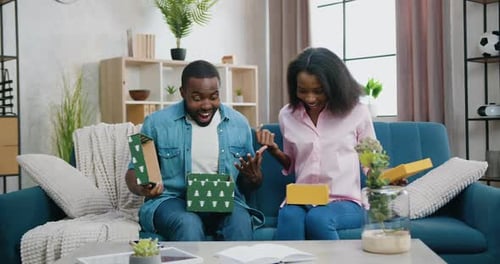Excited Couple Opening Birthday Gifts at Home