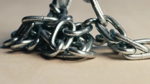 Metal Iron Chain Slowly Falls on a Wooden Table