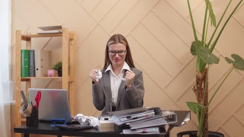 Büroangestellte hält Papier aufgrund von Reizungen und Stress beim Sitzen am Tisch in die Hände