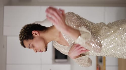 Um homem transexual em um vestido engraçado dançando em um sofá em casa