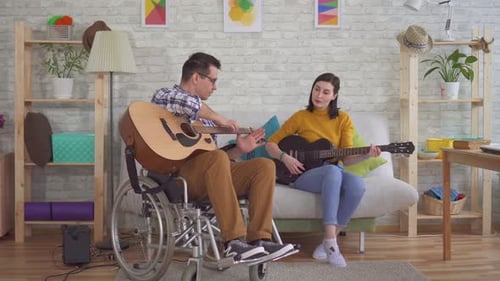 Man in Wheelchair and Woman Playing Guitars