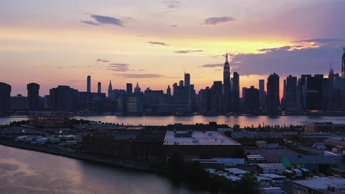 dramatic aerial drone camera pull away & lift over water with New York City's east side in the back