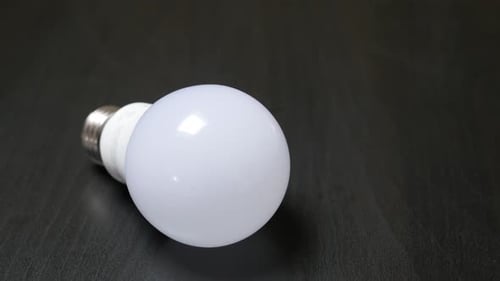 Classic bulb contemporary LED bulb alternative on wooden table slow tilt 4K 2160p 30fps UltraHD foo