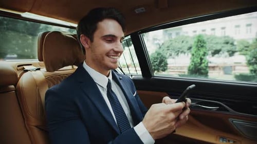 Smiling Man Using Smartphone Inside a Luxury Car