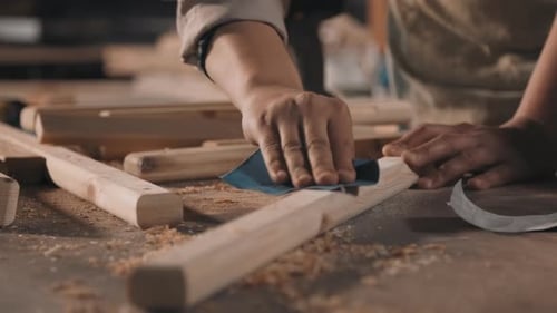 Person sanding a wood plank on a table