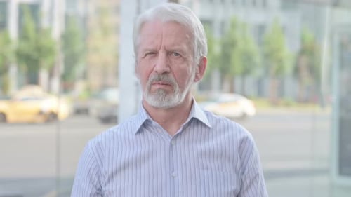 Contemplative Senior Man Looking at Camera in Urban Setting