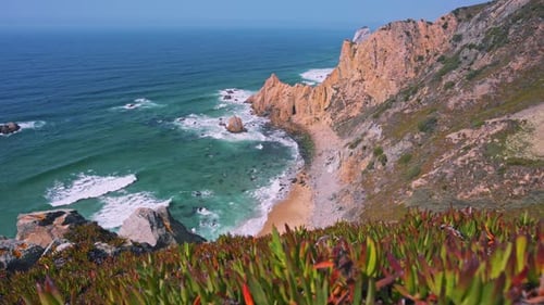 Footage of Praia Do Ursa Beach with Beautiful Orange Colored Cliffs and Foliage in Foreground