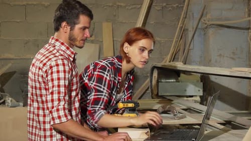 Two Carpenters Using Laptop at Their Workshop While Making Furniture