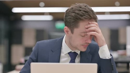 Stressed Businessman Rubbing Temples in Office