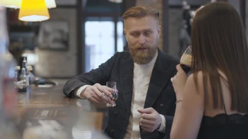 Cute Brunette Woman and Blond Bearded Man Sitting at the Bar Counter Close Up. Concept of Night
