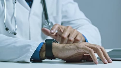 Close up shot of the doctors hand, who uses a smart watch to check the pressure