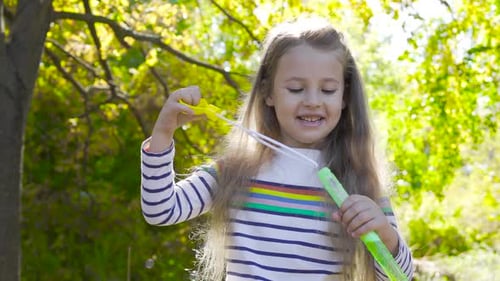 Girl Blowing Bubbles in a Green Park