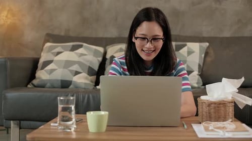 Happy woman using laptop at home on sofa