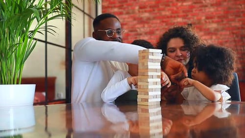 Afroamerikanische gemischtrassige Familie am Tisch, die ein Brettspiel spielt