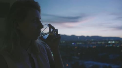 Woman Drinking Water at Night in City Apartment