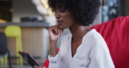 Happy african american woman sitting in cafe using digital tablet and smiling