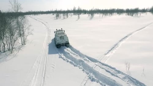All-Terrain Vehicle Driving Across Snowy Field in Winter