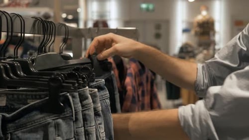 Man Choosing Jeans Pants in Shop. Young Man Buy Choosing Blue Denim Jeans in the Shop