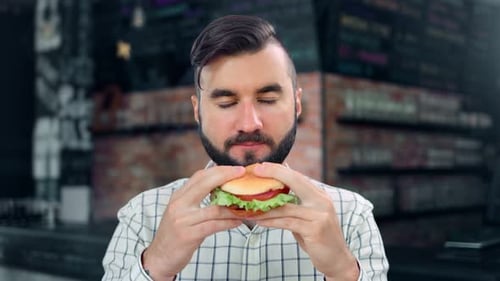 Bearded Man Eating Delicious Burger in Restaurant