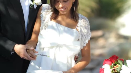 Happy Couple Cutting Wedding Cake Outdoors