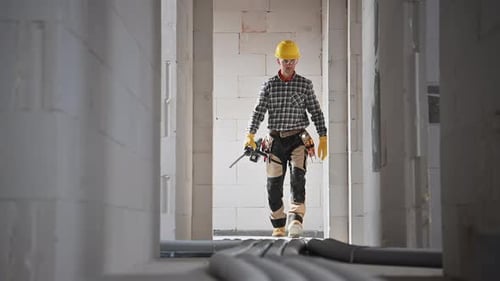 Construction Worker Walks with Power Drill Indoors