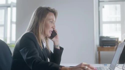 Woman Works at Desk on Laptop and Cellphone