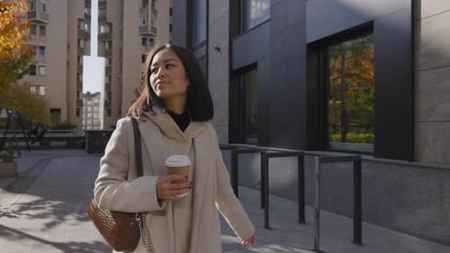 Woman Walks with Coffee on City Street