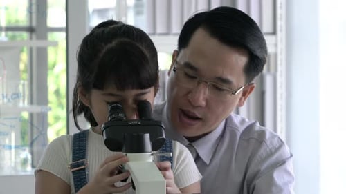 Teacher Helping Child with Microscope Science Experiment