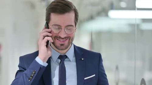 Smiling Man Talking on Cell Phone in Office