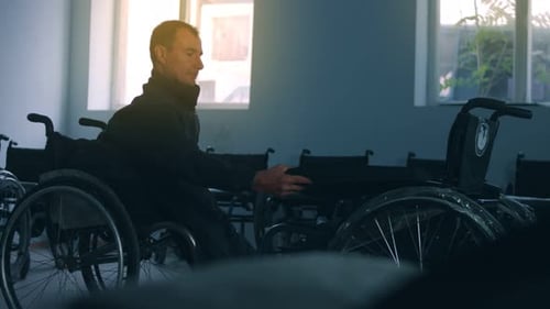 Side View of One American Male Workers in a Workshop at a Factory Making Wheelchairs Sitting at a