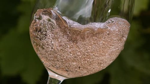 El vino rosado se vierte en un vaso, en cámara lenta