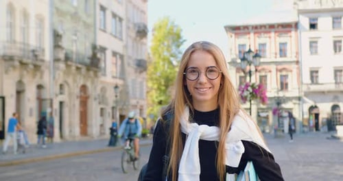 Chica en ropa casual caminando por el centro de la ciudad con edificios antiguos mientras va al trabajo