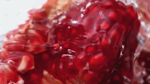 Wasserspritzer auf offenem Granatapfel. Zeitlupe.