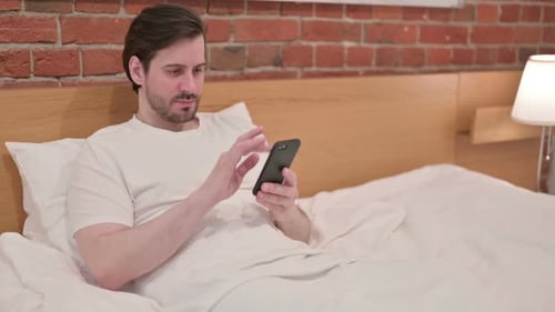 Man Using Smartphone in Bed