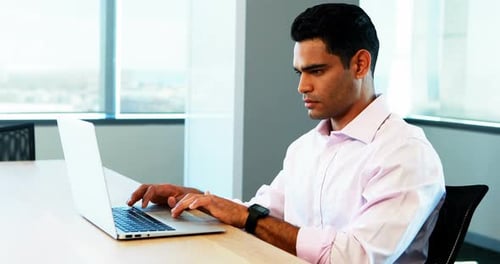 Man Typing on Laptop in Modern Office