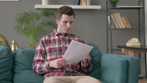 Man Reads Document and Celebrates Good News at Home