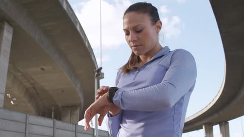 Woman Using Fitness Tracker Watch in Urban Setting