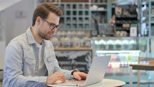 Man Working on Laptop in Cafe Having Video Call