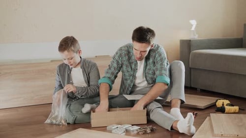 La famille déballe une boîte de pièces d'assemblage de meubles