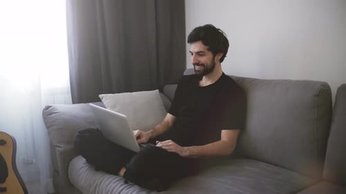 Man Using Laptop on Couch for Video Call
