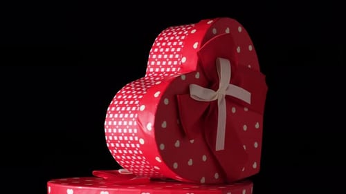 red heart-shaped cardboard box with bow on black background