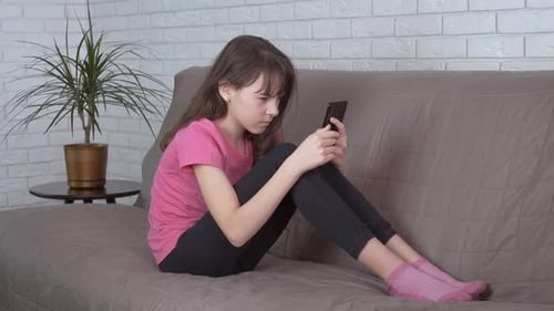 Upset Child Crying with a Phone on Sofa