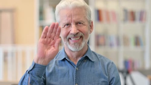 Senior Man Waving and Speaking to Camera
