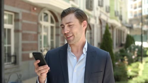 Gros plan Homme d'affaires souriant avec téléphone dans la rue. Homme tapant un message en extérieur