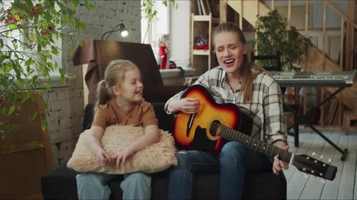 Woman Playing Guitar for Young Child at Home