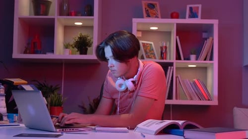 Student Studying Late at Desk with Laptop and Books