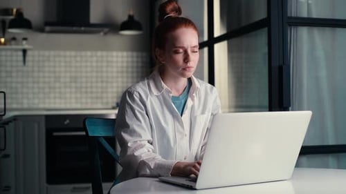 Woman With Neck Pain Working on Laptop at Night