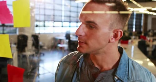 Man Brainstorming Ideas on Glass Wall in Office